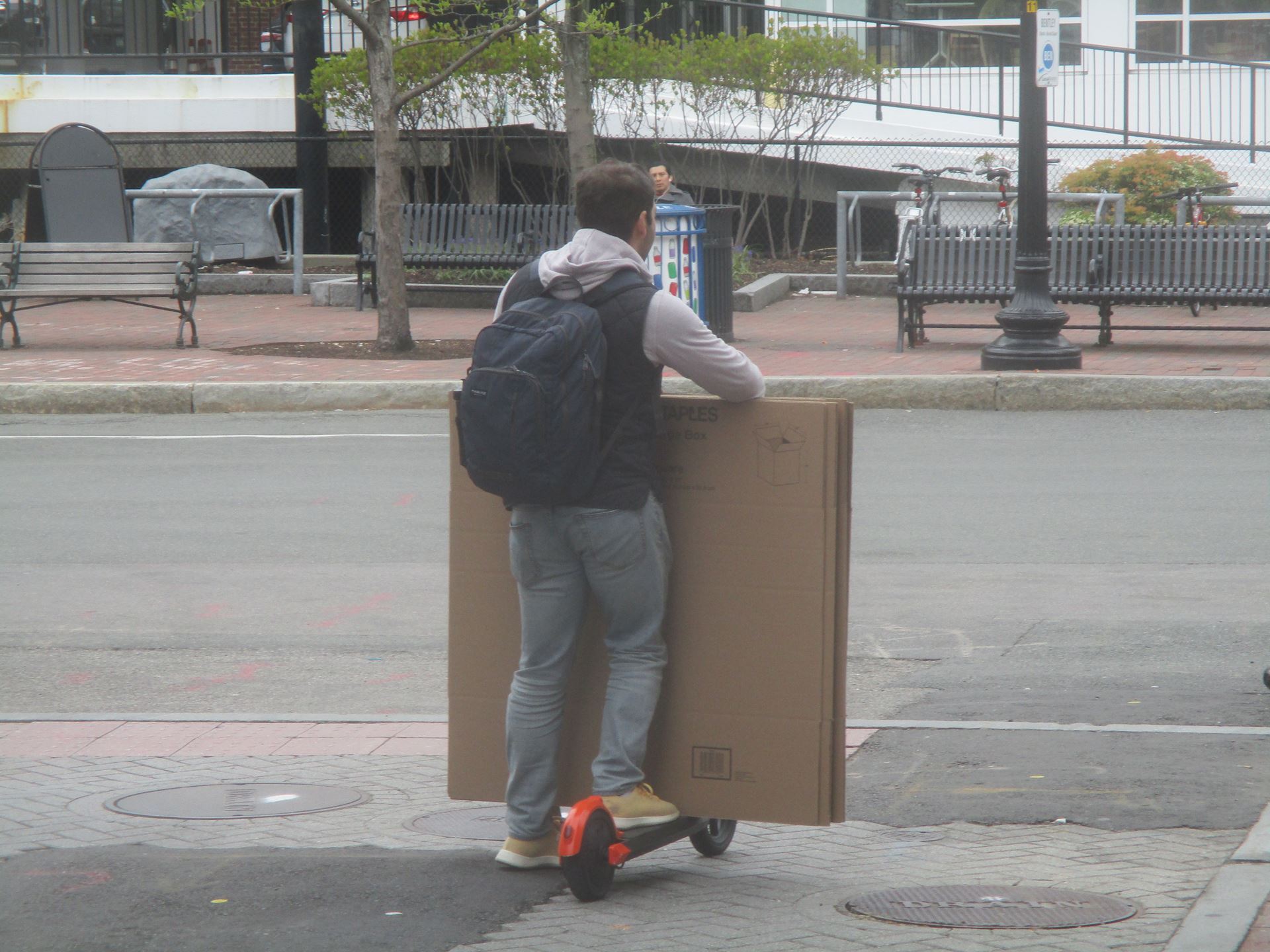 Man riding a scooter with large cardboard boxes